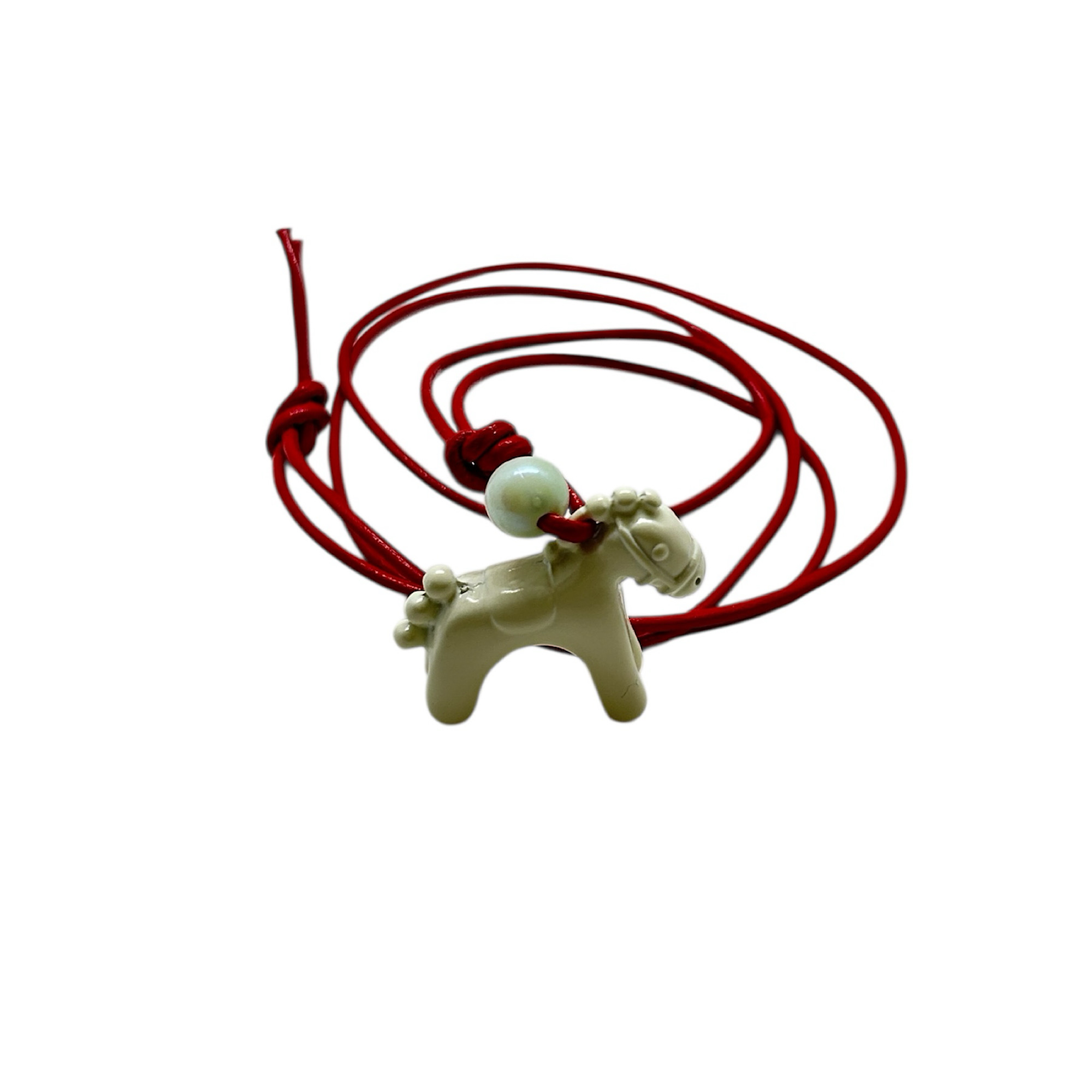 Pendant with red cord and white enamel horse.